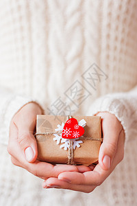 拿着礼物的针织毛衣的女人 礼品包装在带有白色毛毡雪花和红色心形的牛皮纸中 DIY 方式包装圣诞礼物 手 盒子图片