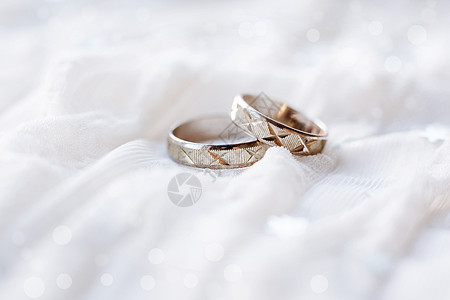 白色布料背景的婚环和闪亮的bokeh背景图片