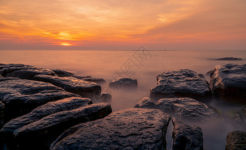 日落时在石滩上的岩石 美丽的海滩夕阳天空 石头 海岸线图片