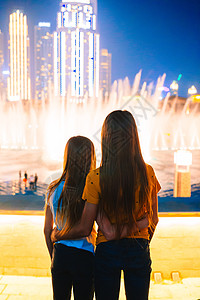 小女孩们在迪拜看传奇的歌唱喷泉表演 高的 水图片