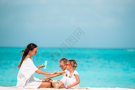年轻母亲在沙滩上给女儿鼻子涂防晒霜 保护太阳 脸 身体护理图片