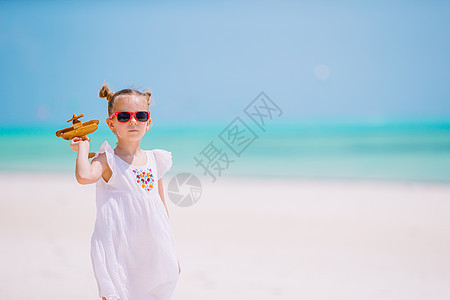 带玩具飞机的快乐小女孩 在白沙滩上手握着玩具飞机 乐趣 快乐的图片