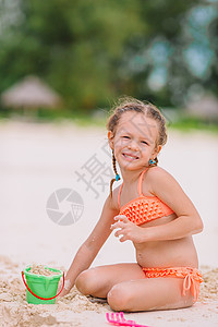 在热带度假期间玩沙滩玩具的可爱小女孩 热带假期 绿松石 水图片
