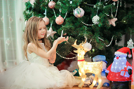 在圣诞树附近的可爱的小女孩 圣诞树下的孩子们带着礼品盒 礼物 季节图片