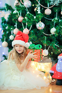 在圣诞树附近的可爱的小女孩 圣诞树下的孩子们带着礼品盒 庆典 家图片