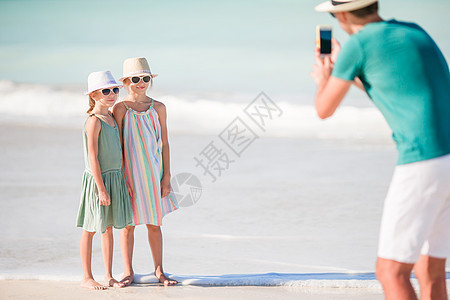 男人在海滩上拍孩子的照片时 海滨 父母 热带 女儿图片