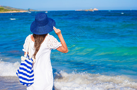 在热带海滩带草帽和蓝条纹袋的年轻女孩 泳装图片