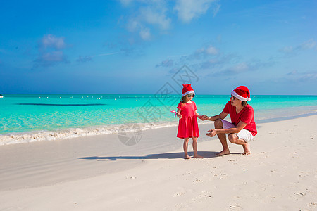 在奇异海滩的圣塔帽子 圣诞礼堂的小女孩和快乐爸爸 圣诞节 冬天图片