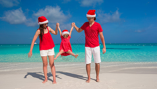 圣诞礼帽三三人的幸福家庭 在白沙滩玩得开心 微笑 好玩的图片