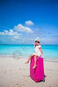 穿着温暖冬帽和手套的可爱女孩在海滩上带着行李行走 海岸 童年图片