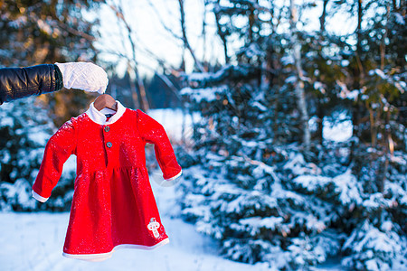 孩子的红色圣诞老人礼服 在一个雪雪碧的森林里 裙子 帽背景图片