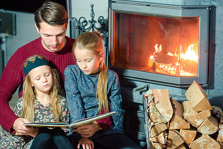 圣诞节前夕在壁炉附近的一家人一起阅读一本书图片