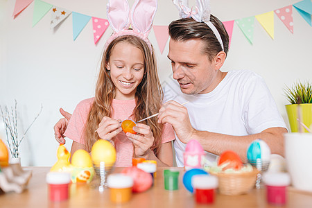 父亲和他的小女儿在画鸡蛋 幸福的家庭准备复活节了 传统 游戏图片