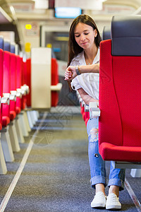年轻快乐的女孩看着火车的轮车手表背景图片