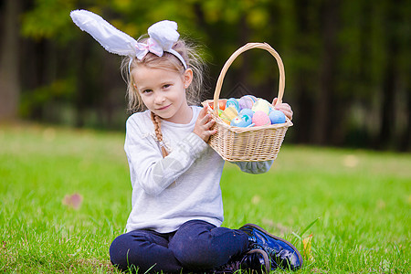 有魅力的小女孩 穿着兔子耳朵 在春日露天外出城时 带着一篮子复活节鸡蛋图片