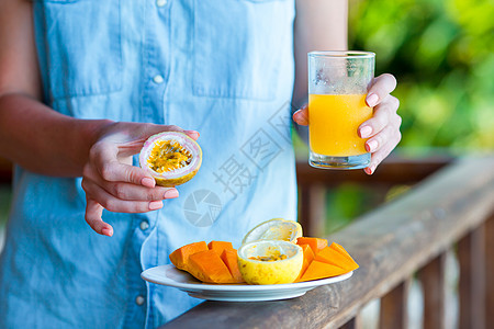 美味的异国情调水果 — 成熟的百香果 女性手中早餐时的芒果图片