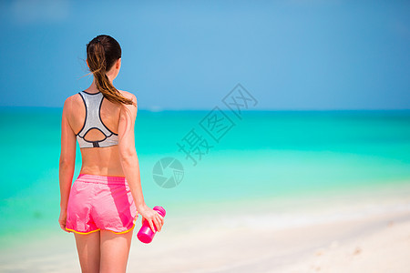 在白沙滩上喝着一瓶水的漂亮女孩 热带 自由的 慢跑图片