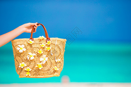 紧贴的漂亮包袋 上面有青木马尼花朵 在海面背景图片