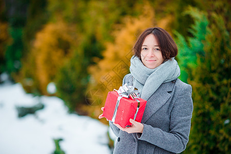 在冬日户外带红圣诞节礼物的女子图片