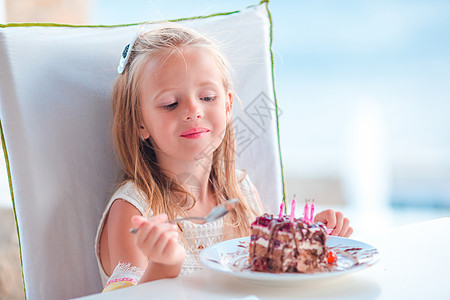 小女孩在户外咖啡厅庆祝生日快乐 吃着美味的蛋糕 礼物 食物图片