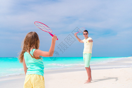 在白色热带海滩上和父亲打网球的小女孩儿 运动图片