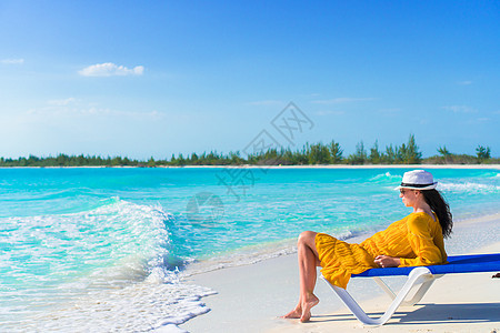 在热带沙滩上戴帽子的年轻女人 晒着阳光放松图片