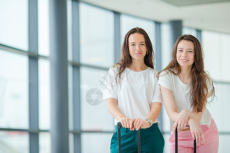 带着行李的年轻旅游妇女在国际机场带着她的行李走路 航空公司乘客在机场休息室等待飞行飞机 航班 自由背景