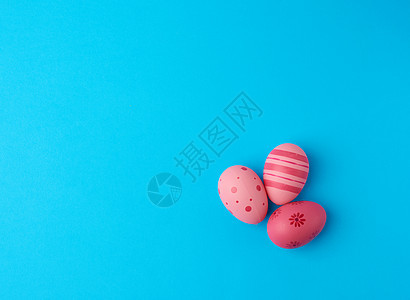 蓝色背景上的三个彩色粉红色复活节彩蛋图片