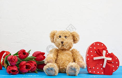 棕褐色可爱泰迪熊坐在蓝木背景 花束上 乐趣图片