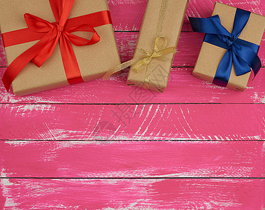 包着棕色奶粉纸和丝带 粉红木头的礼品图片