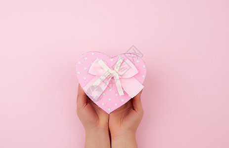 女性手握着粉色纸板盒 在粉红色面包上弓 礼物图片