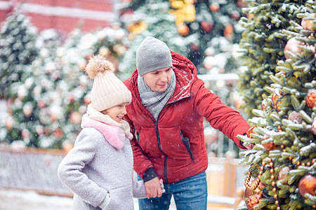 新的一年 在雪地的fir -tree树枝附近的小快乐女孩 礼物 父亲图片