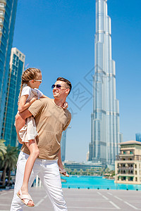 一家人快乐地在迪拜走来走去 背景中还有摩天大楼 天空 水图片