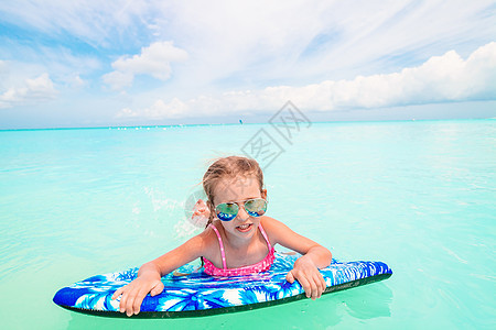 小女孩在海中用可充气的空气床垫放松 冲浪 游泳衣图片