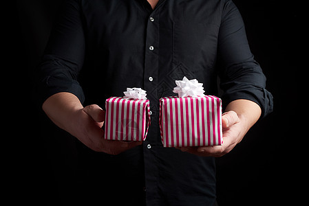 穿黑衬衫的成人男子手上握着一堆纸笔 礼物盒 假期图片