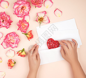 两只母手把红心放在白纸封里 花的 花束 爱 桃图片