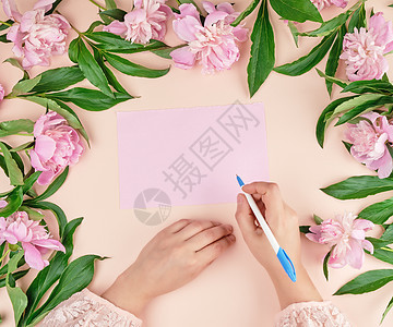 女性手握着一只白笔 在空粉红色的帕皮平原上 写 纸图片