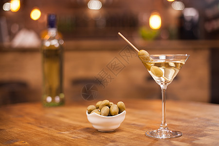 杯子里的马丁尼 旁边有橄榄 就在一个生锈的木制桌子上 饮料 新鲜图片