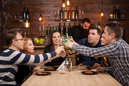 快乐的朋友们团体 喝啤酒和吃披萨 在酒吧餐厅图片