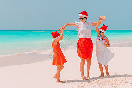 在庆祝圣诞节的热带海滩上 戴红色圣诞老人帽子的美丽家庭快乐 岛 加勒比图片