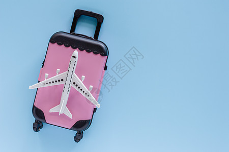 白色飞机型号 蓝色背景的粉红色手提箱图片