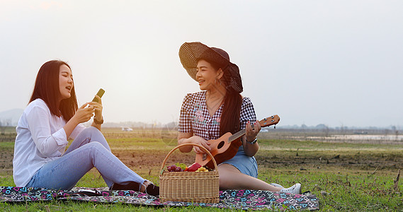 一群亚洲朋友玩Ukelele Ukelele 并花时间在暑假野餐 他们很快乐 自拍 节日旅行时间比较慢 快乐的 假期图片