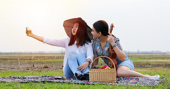 一群亚洲朋友玩Ukelele和花点时间 海滩图片