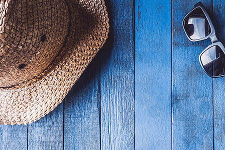 带有太阳墨镜的帽子 蓝漆木板背景 文字空闲空间背景图片