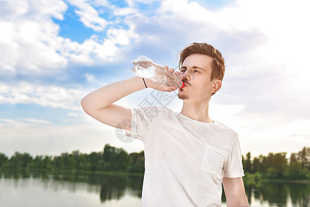 年轻人在湖边和森林背景下喝淡水 夏日口渴 他想喝点水 他想要喝酒 海 食物图片