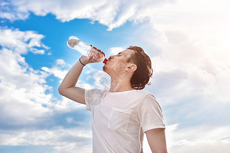 年轻人在湖边和森林背景下喝淡水 夏日口渴 他想喝点水 他想要喝酒 健康 假期图片