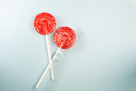 圆形红色甜甜美味的棒棒糖 蓝面糊背景图片