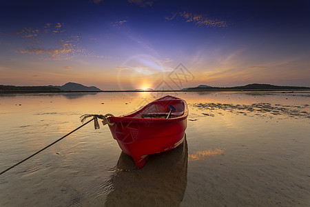 太阳升起的清晨时间独自在沙滩和低海面上的红色渔船图片