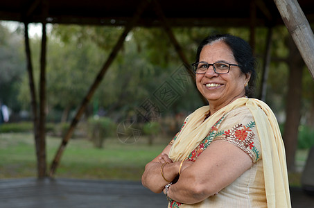 在印度新德里的夏天 穿着灰白色萨尔瓦卡米兹旁遮普西装的公园里 聪明自信的北印度高级女性站着 双手交叉/折叠在镜头前摆姿势图片