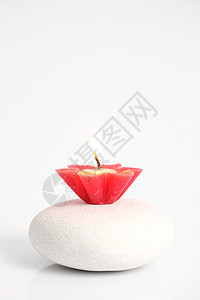 白背景孤立的石上花朵蜡烛图片